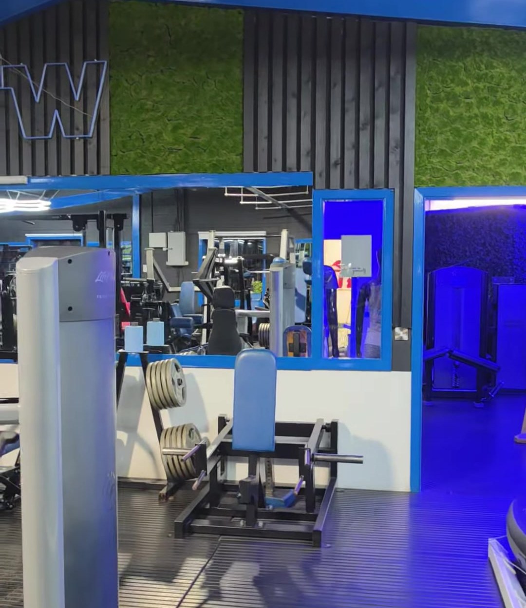 The reception area with a green moss wall and a blue-lit doorway